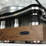 IsoAcoustics DELOS 1815W1 walnut isolation platform with turntable above, showing a rich walnut finish.
