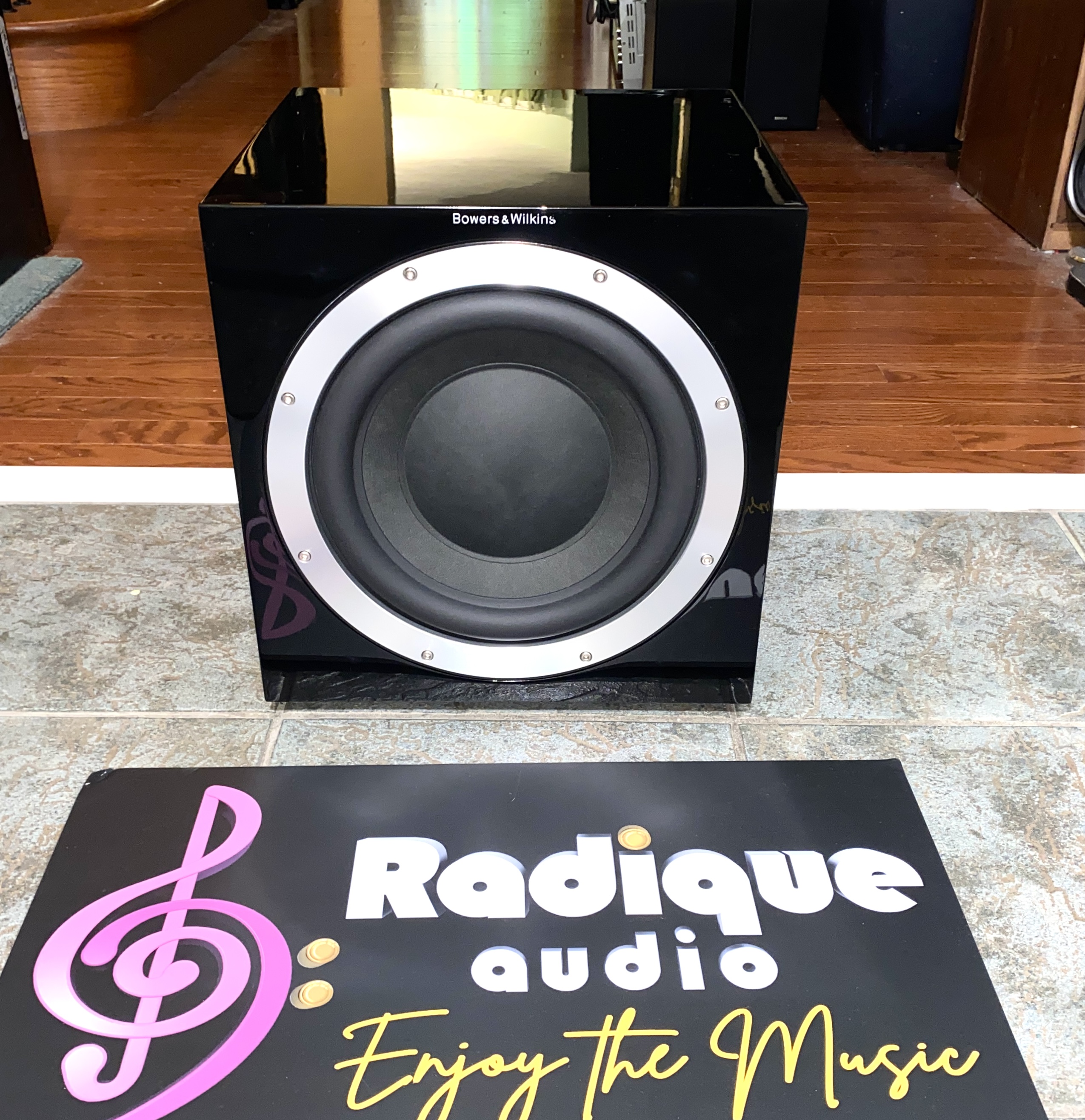 BW-ASW-10CM-01 B&W ASW 10CM subwoofer in gloss black — front view with the grille removed, showing the 10-inch driver