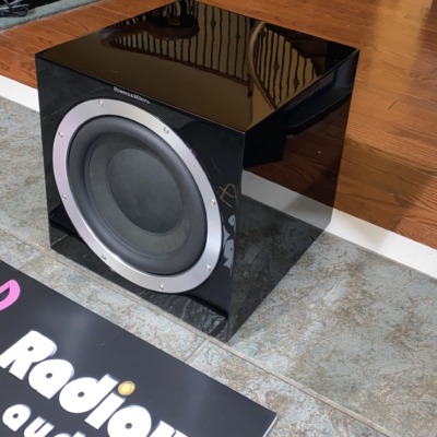 B&W ASW 10CM subwoofer — angled view showing the gloss black cabinet and driver surround