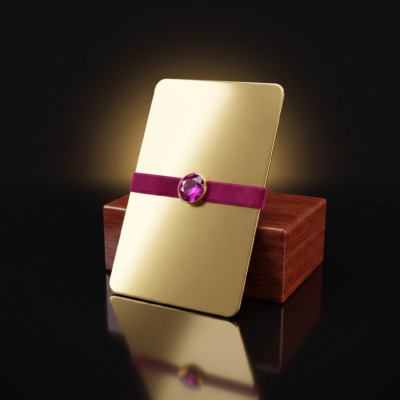 Polished brass gift card with a magenta ribbon and jewel, resting against a rosewood block — Radique Gift Cards category icon