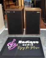 Avant 1AX speakers with their black cloth grilles and gold Avant badges fitted, in walnut cabinets