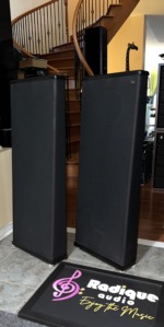 Angled view of the DCM TimeFrame TF350 towers showing their slim black cabinets and wrap-around grille fabric