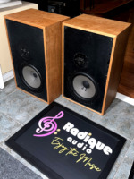 Pair of Dynaco A-35 speakers from an angle, figured cherry grain across the tops and side panel beside the black front baffles