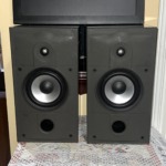 Energy Connoisseur C-2 bookshelf speakers in high gloss black with grilles off, showing the tweeter, silver-cone woofer and front bass port