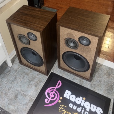 Pair of Fisher XP-65S speakers turned at an angle, walnut veneer sides and tops visible beside the tan driver baffles