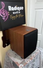 JBL Northridge E150P subwoofer at an angle with the grille on, cherry cabinet sides and a black cloth front