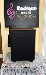 JBL Northridge E150P powered subwoofer straight on with its black cloth grille fitted over the cherry cabinet