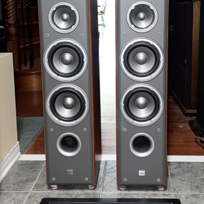 Pair of JBL Northridge E80 tower speakers in cherry with grilles off, showing the tweeter, midrange, twin woofers and front port