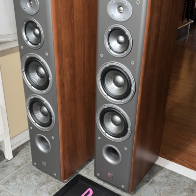 Angled view of the JBL Northridge E80 towers, grilles off, showing the cherry side panels and grey front baffles