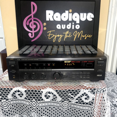 JVC RX-307 stereo receiver, black front panel with power and speaker switches, bass, treble and balance dials, a large volume knob and a lit tuner display