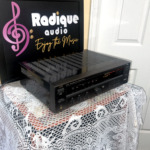 JVC RX-307 receiver seen from the left at an angle, showing the vented black top cover, the slim faceplate and the Radique board behind it