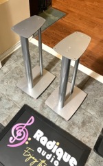 Pair of Linn 25 inch metal speaker stands in silver at an angle, twin pillars between a top plate and a wide base