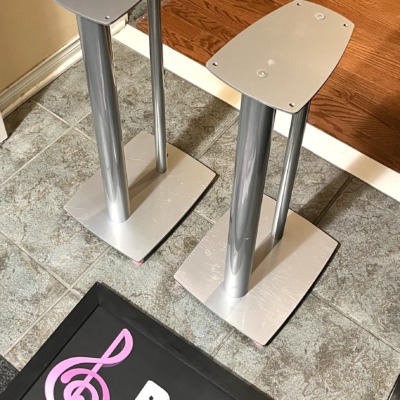 Pair of Linn 25 inch metal speaker stands in silver at an angle, twin pillars between a top plate and a wide base