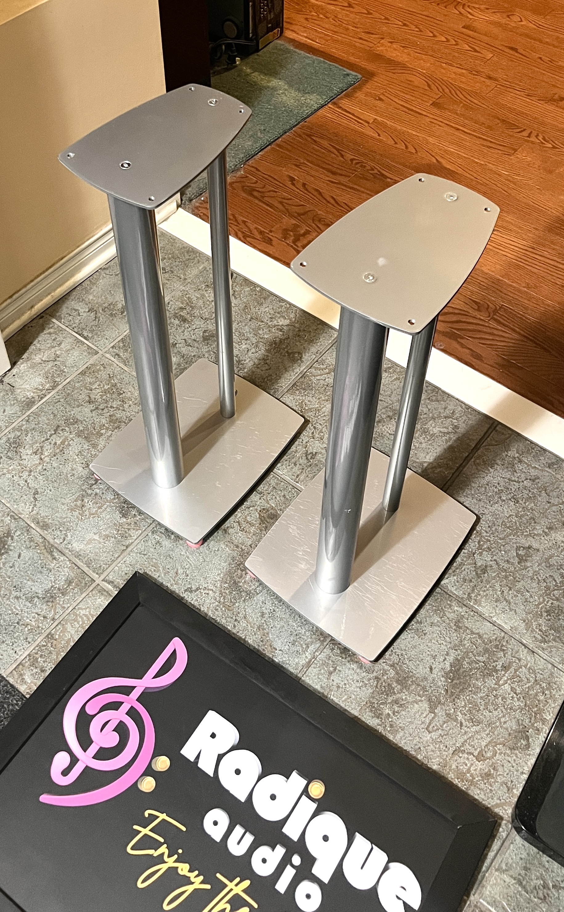 Linn-25″-Metal-Speaker-Stands-Silver-Front-Angle Pair of Linn 25 inch metal speaker stands in silver at an angle, twin pillars between a top plate and a wide base