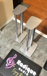 Linn silver metal speaker stands from the side, showing the twin pillars, shaped top plates and wide base plates