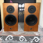 Pair of Linn Katan bookshelf speakers in cherry-toned wood veneer, front baffles with a recessed dome tweeter, mid-bass driver and oval LINN badge