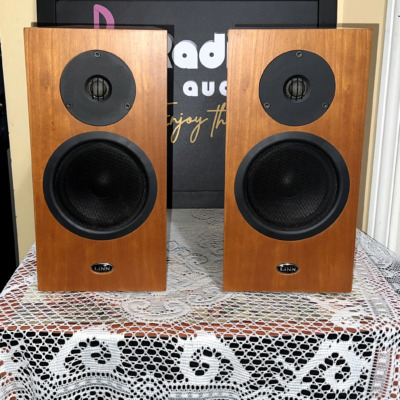 Pair of Linn Katan bookshelf speakers in cherry-toned wood veneer, front baffles with a recessed dome tweeter, mid-bass driver and oval LINN badge