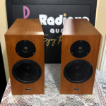 Linn Katan speaker pair at a slight angle, wood cabinets showing their top panels above the recessed tweeter and grille-covered bass driver