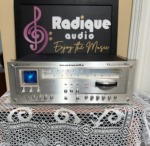 Marantz 2130 tuner powered on, blue dial glowing and a trace on the oscilloscope screen, rows of silver toggle switches and rotary knobs below