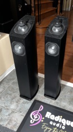 Mirage OMNI 350 towers in black ash at an angle, grilles off, standing on tile beside the Radique board