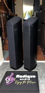 Angled view of the Mirage OMNI 350 towers with grilles on, showing the curved black ash cabinets