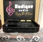 Nakamichi 500 cassette deck, black top panel with twin yellow-lit VU meters, slider level controls and transport keys, dark wood end cheeks