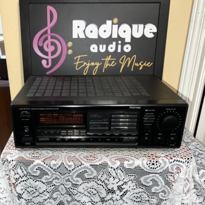 Onkyo TX-906 stereo receiver in black, front panel with display and volume knob, on lace in front of the Radique board