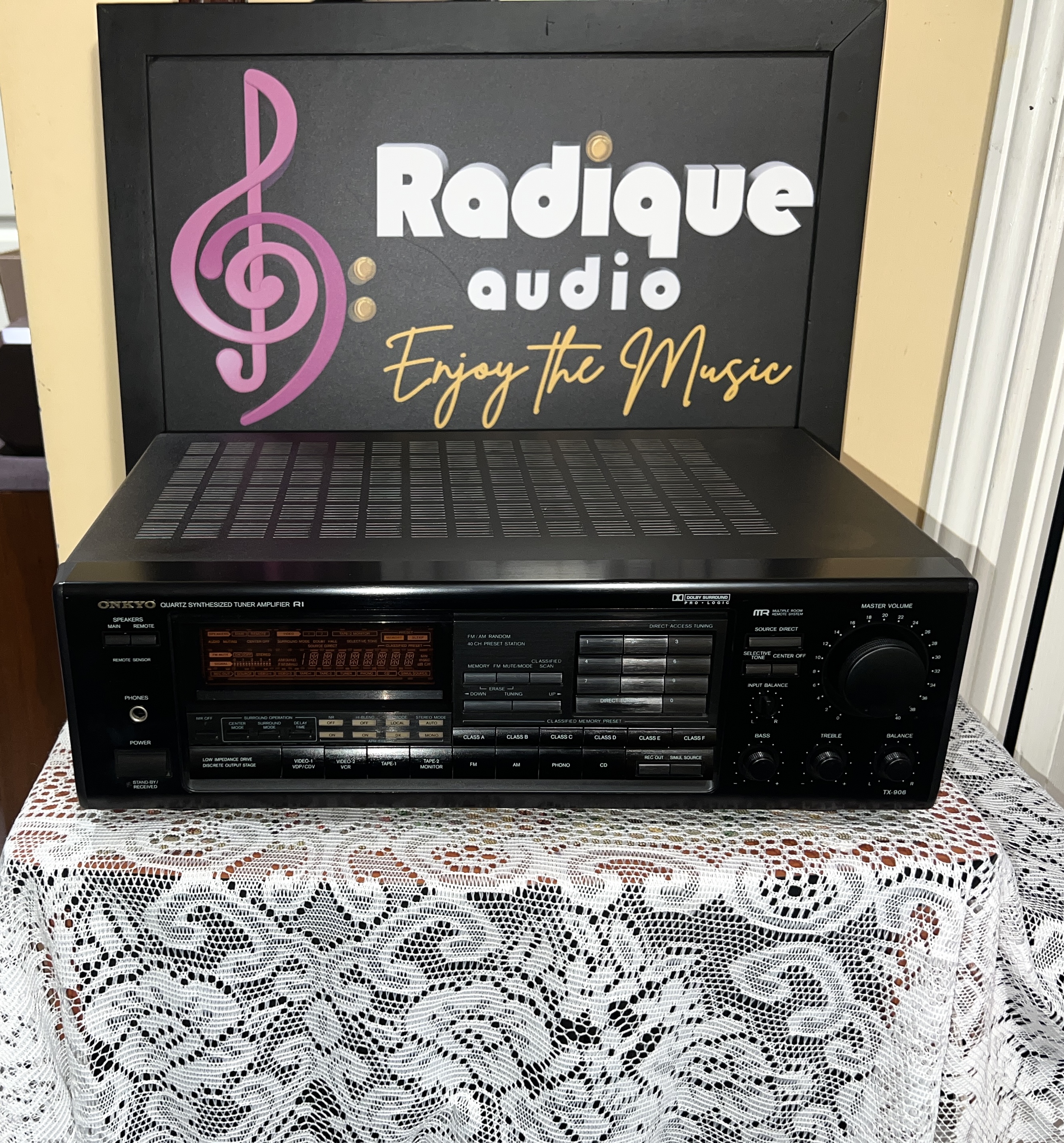 Onkyo-TX-906-Stereo-Receiver-Front Onkyo TX-906 stereo receiver in black, front panel with display and volume knob, on lace in front of the Radique board