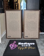 Original Large Advent speakers with the linen grilles fitted, walnut cabinet edges framing the cloth and a small ADVENT badge on each