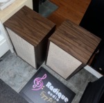Original Large Advent speakers with grilles fitted, viewed from above at an angle so the walnut tops and one side panel are visible