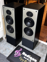 Paradigm 11se Mk II speakers at a three-quarter angle, black wood-grain side panels and tops beside the grey three-driver front baffles