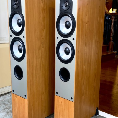 Paradigm Monitor 7 v2 towers at an angle with grilles on, slim light cherry cabinets and black cloth fronts