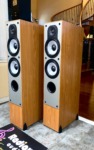 Paradigm Monitor 7 v2 towers at an angle with grilles on, slim light cherry cabinets and black cloth fronts