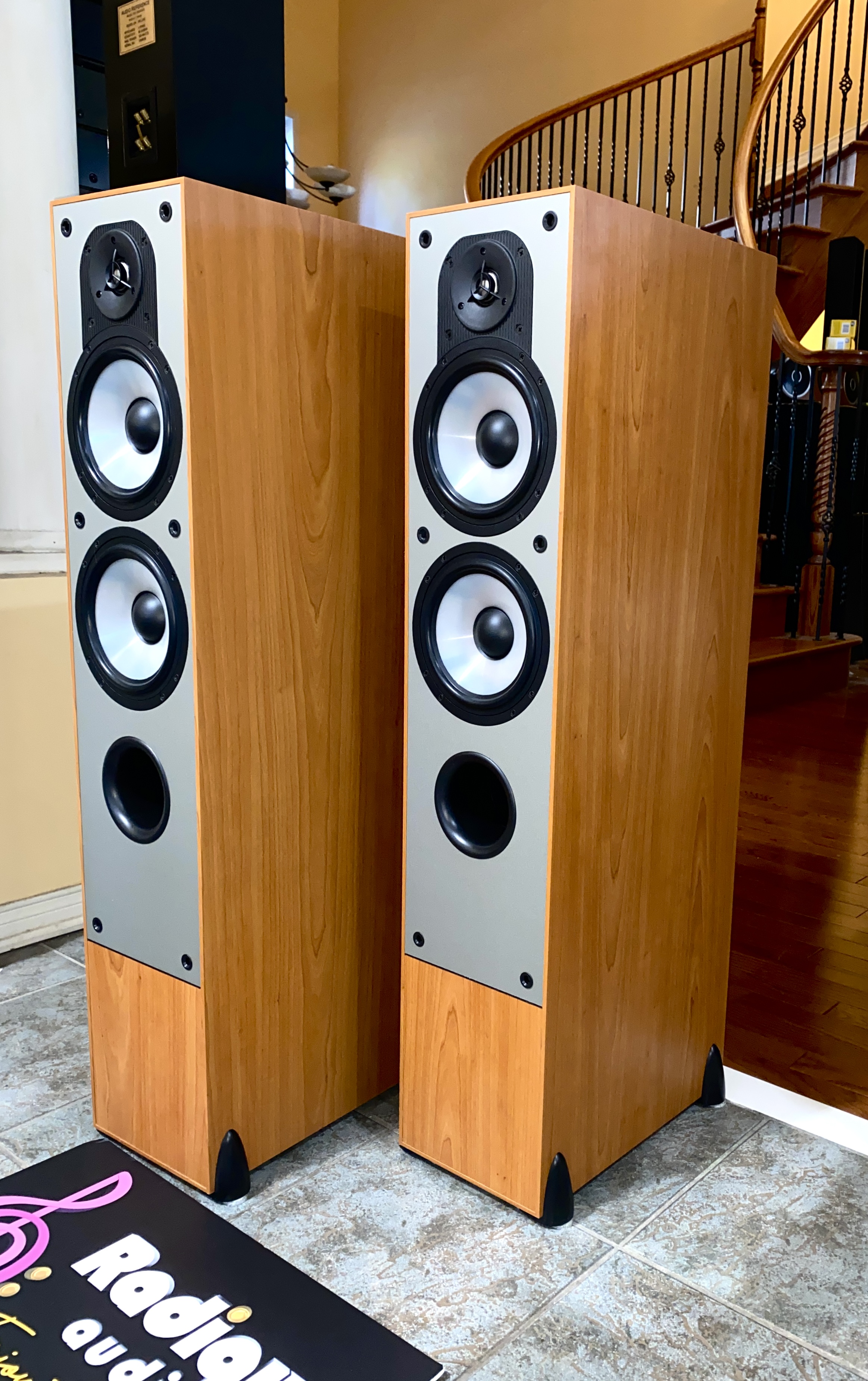 Paradigm-Monitor-7-v2-Floorstanding-Speakers-Light-Cherry-Front-Angle Paradigm Monitor 7 v2 towers at an angle with grilles on, slim light cherry cabinets and black cloth fronts