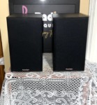 Pair of Paradigm Titan bookshelf speakers in black with cloth grilles fitted and the Paradigm logo on each grille