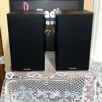 Pair of Paradigm Titan bookshelf speakers in black with cloth grilles fitted and the Paradigm logo on each grille