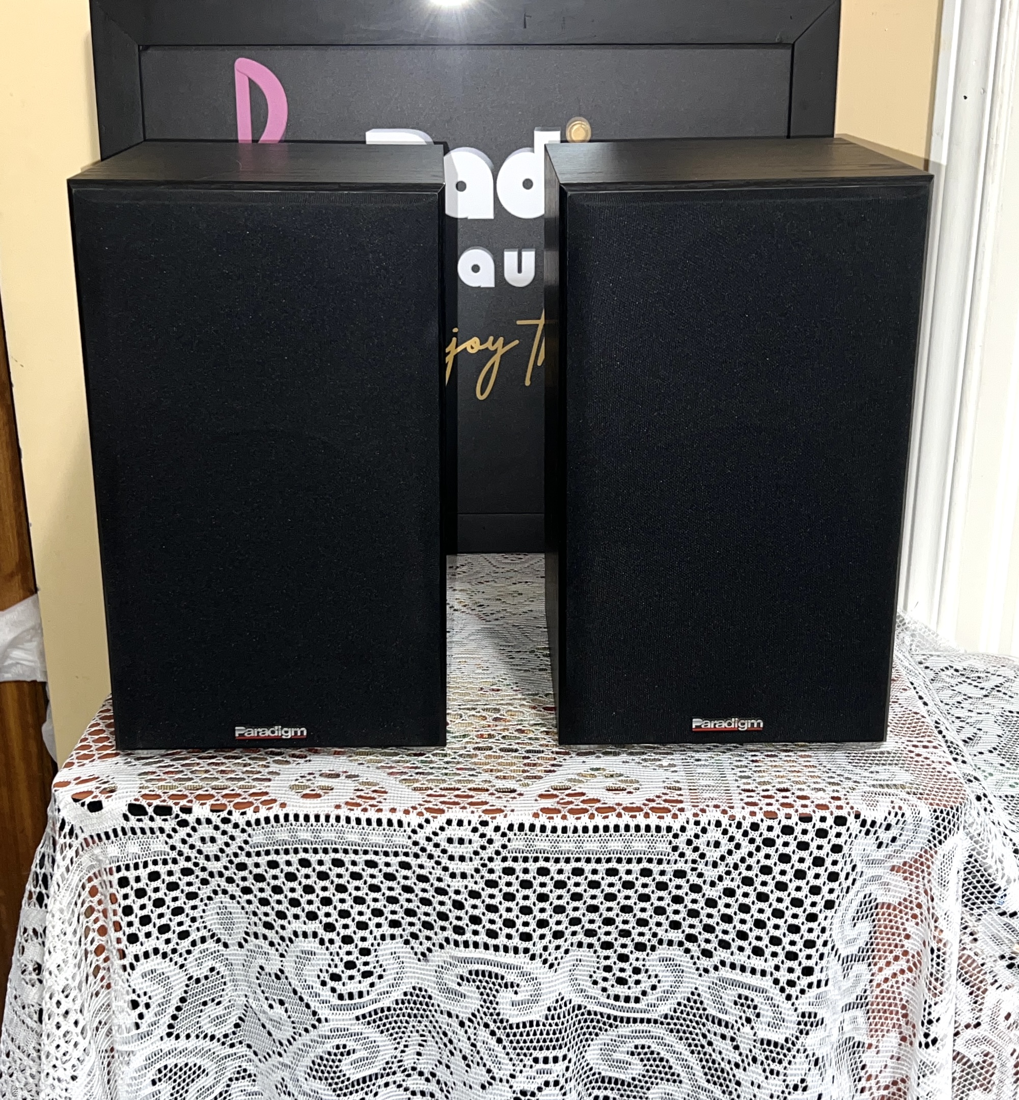 Paradigm-Titan-Bookshelf-Speakers-Front Pair of Paradigm Titan bookshelf speakers in black with cloth grilles fitted and the Paradigm logo on each grille