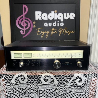 Sansui TU-5900 AM/FM stereo tuner, black faceplate with a backlit tuning scale, twin signal meters and a large centre tuning knob
