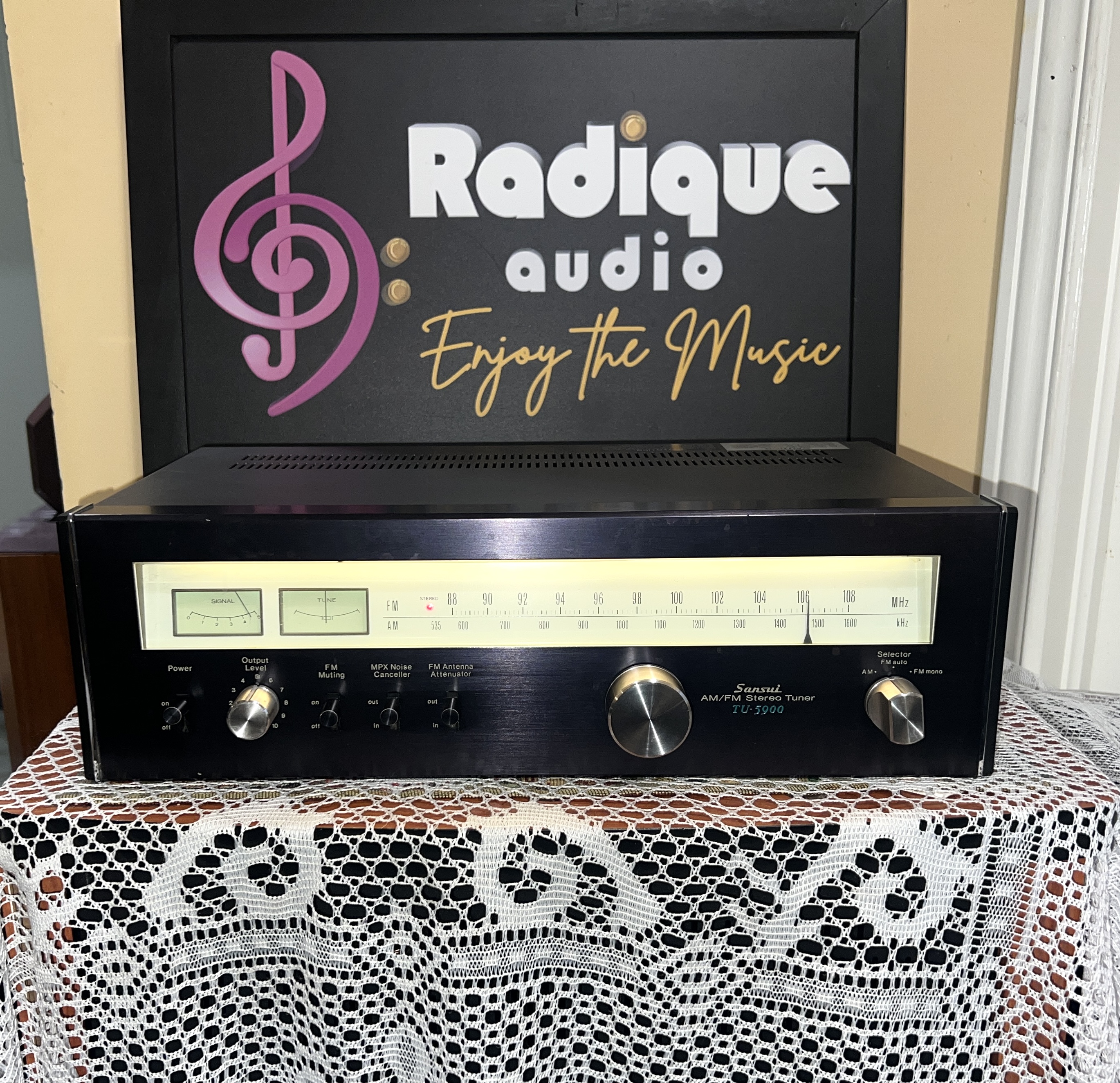 Sansui-TU-5900-AM-FM-Stereo-Tuner-Front Sansui TU-5900 AM/FM stereo tuner, black faceplate with a backlit tuning scale, twin signal meters and a large centre tuning knob