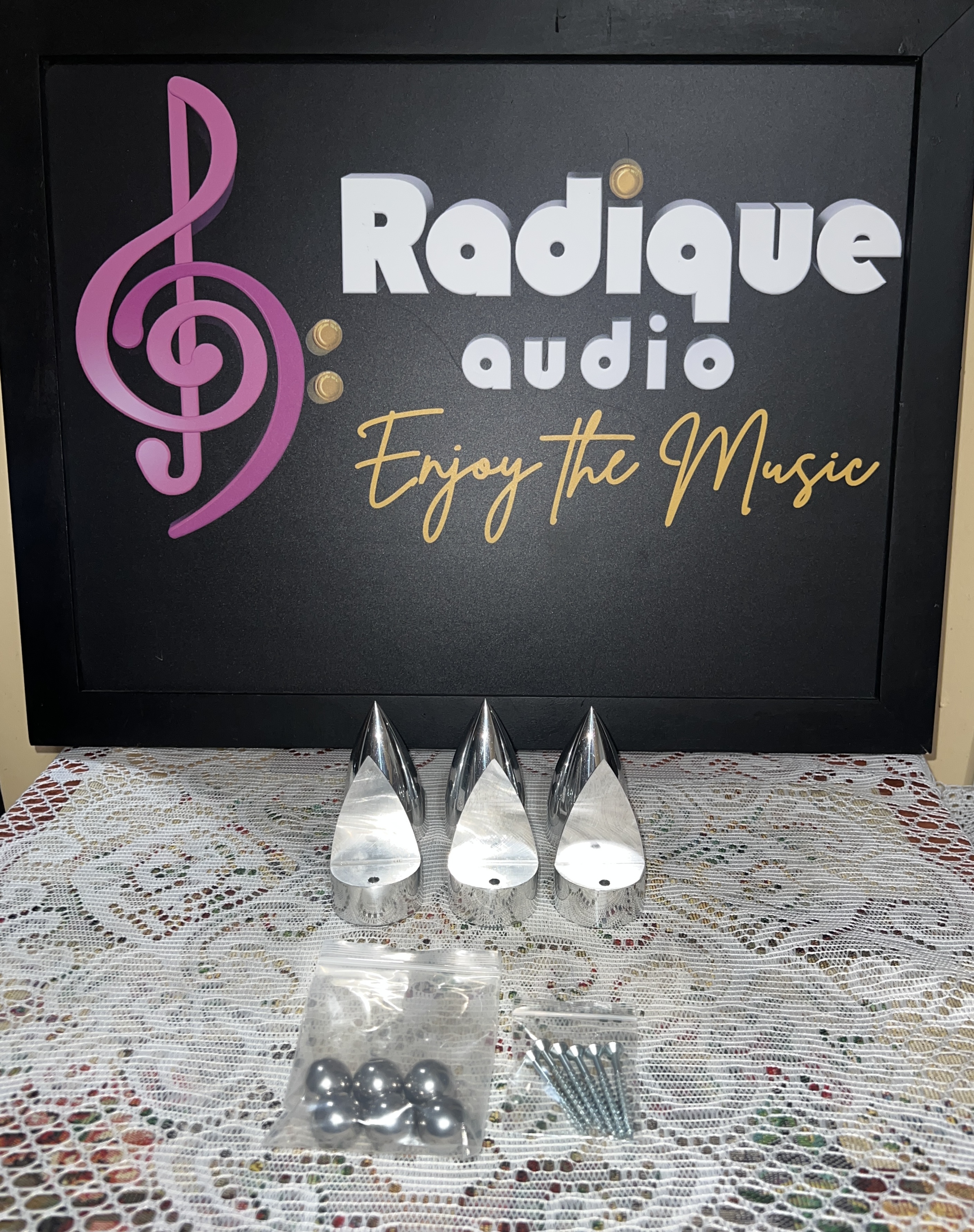 Totem Claw Feet Set of six silver Totem Claw machined aluminium isolation feet with a bag of ball bearings and self-tapping screws, in front of the Radique Audio sign