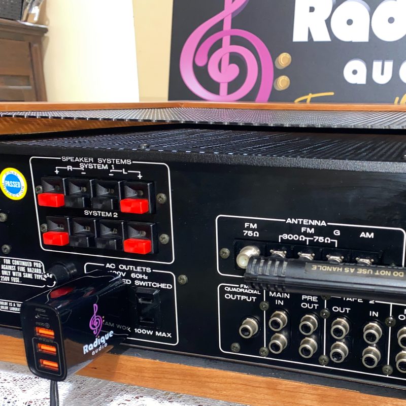 Radique Audio RA-USB charger plugged into the AC outlet on the back panel of a vintage receiver