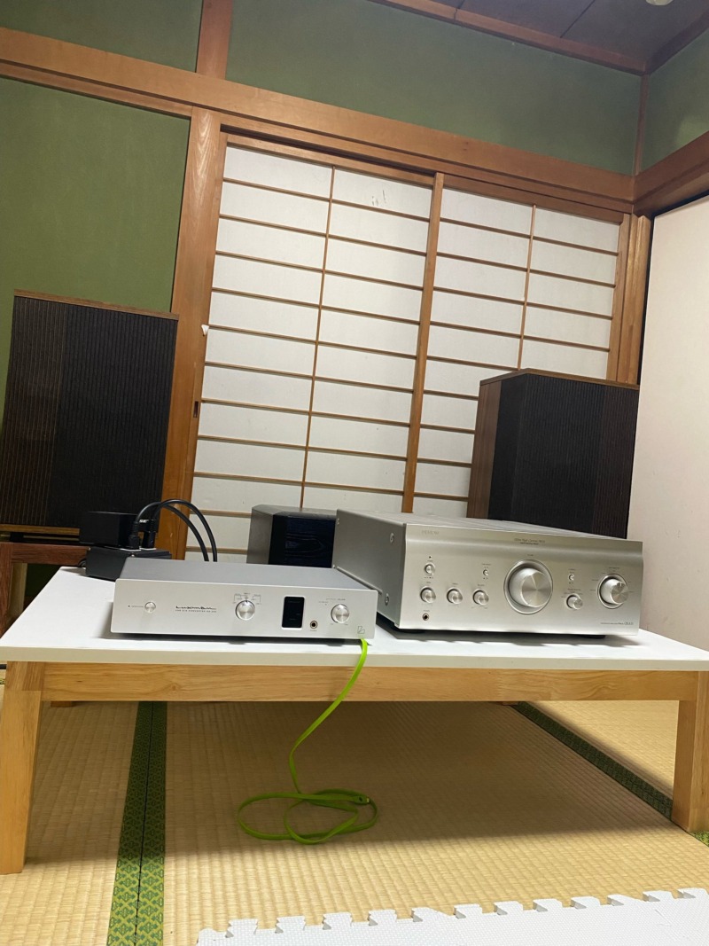 Audio Japan’s listening room in Japan: two silver amplifiers on a low white table, tall wood-cabinet speakers, tatami mats and shoji screens