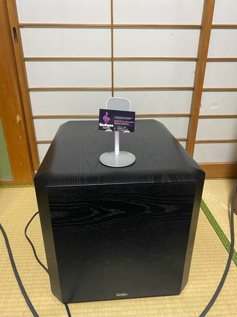 The Paradigm PS-1000 subwoofer from Radique on a tatami floor in Japan, with a Radique business card displayed on top