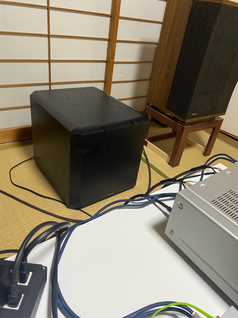 The Paradigm PS-1000 subwoofer beside a wood-cabinet speaker on a stand, in a tatami room in Japan