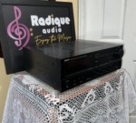 Denon DRA-835R receiver seen from a front angle, black case on lace in front of the Radique backdrop