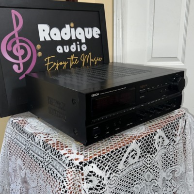 Denon DRA-835R receiver seen from a front angle, black case on lace in front of the Radique backdrop