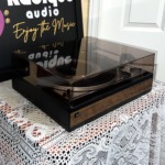 Angled view of the Dual 1214 with the smoked dust cover closed, showing the hinged lid and walnut-grain base trim