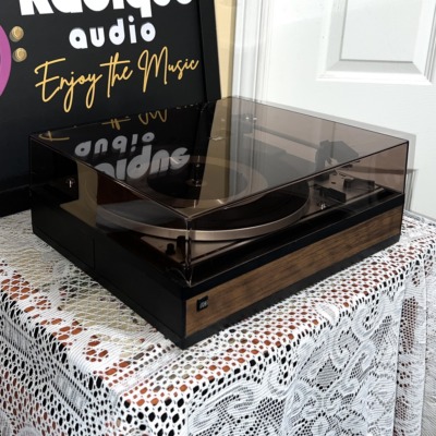 Angled view of the Dual 1214 with the smoked dust cover closed, showing the hinged lid and walnut-grain base trim
