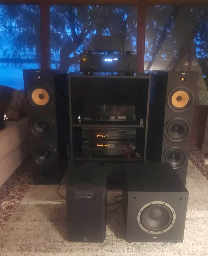 Ed W.’s system in Ontario: B&W DM604 S1 towers flanking a black component cabinet with a turntable and electronics, plus B&W and Yamaha subwoofers