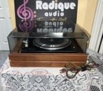 Garrard Synchro-Lab 65B turntable seen from the rear, dust cover in place, with its brown power cord and green ground wire coiled beside the base